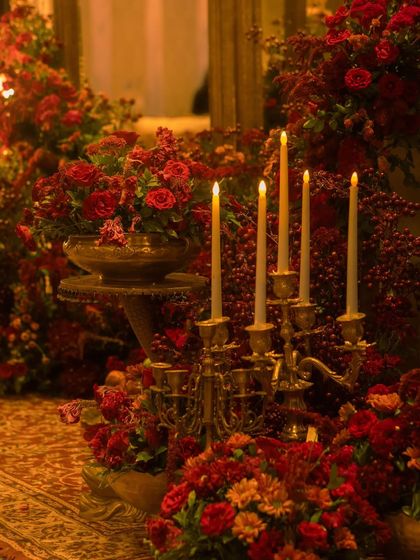 Romance is in the details. We used antique style brass candelabras with tall taper candles, nestled within lush red floral arrangements, to add a layer of warmth and classic elegance to the reception decor.