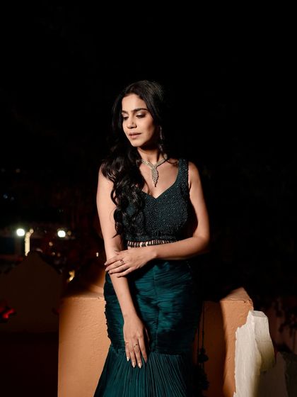 A moody, low-light shot of the teal lehenga, creating a sense of drama and elegance for an evening event.