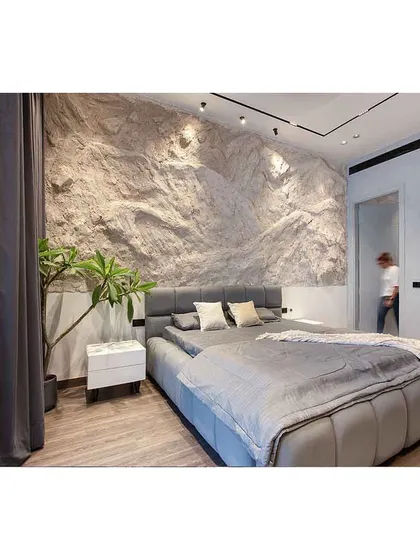 A person walks through the bedroom, giving a sense of the room's scale and the seamless integration of the hidden door next to the rock-textured wall.