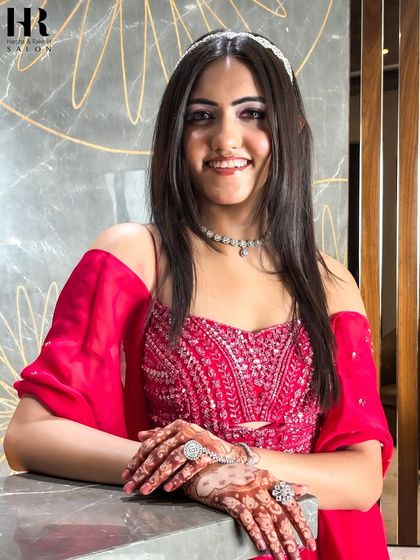 Posing with confidence, this client shows off her flawless party makeup and intricate henna. Her hands are beautifully adorned, ready to be the center of attention at any event.