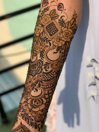 A close-up of a forearm showcasing a mix of my favorite elements: bold roses, leafy vines, and geometric checkerboard fills.