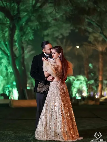 A reception portrait set against the enchanting green-lit woods. The groom's tender embrace and the bride's elegant gown create a fairytale-like image, capturing the magic of their celebration.