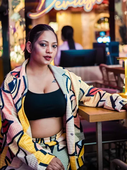 A guest in a colorful jacket, sitting at a table near the DJ booth.