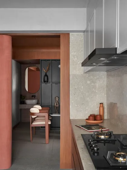 A dusty terracotta lime-washed curved wall marks the entry to the kitchen, adding an earthy, welcoming touch. This detail shows how I use natural materials and color to define and connect different zones in a home.