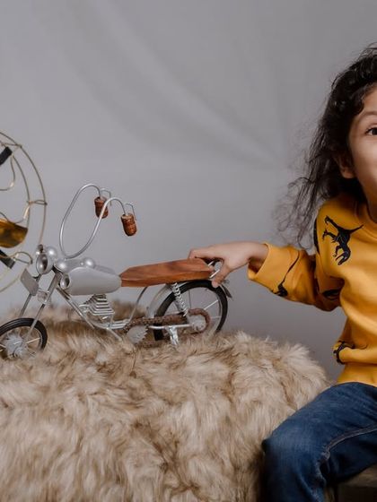 A portrait of a young boy with long, curly hair, looking curiously at the camera. Our studio sessions are perfect for capturing simple, beautiful portraits that highlight your child's unique features.