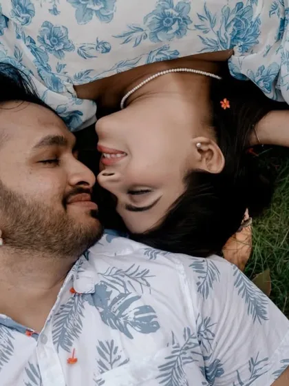 An intimate overhead shot of the couple lying on the grass. Their closeness and serene expressions create a beautiful and romantic image that feels very personal and peaceful.