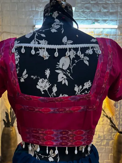 The back of the blouse has a beautiful design with cowrie shell tassels.