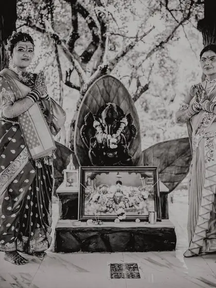 A bride and her mother standing before the family deity, seeking blessings together. A moment of shared faith and tradition.