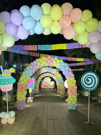 The view through the 'Candy Land' balloon tunnel, lined with lollipop and ice cream props, creating a sweet pathway for guests.
