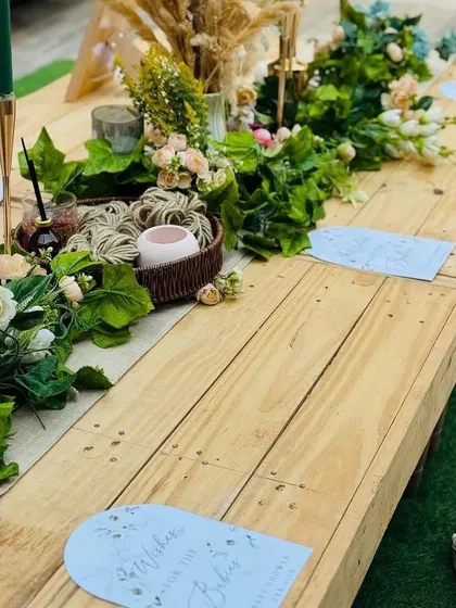 We designed a low-seating picnic-style table for a relaxed and intimate boho baby shower. The wooden table is adorned with a green garland and personalized place cards.