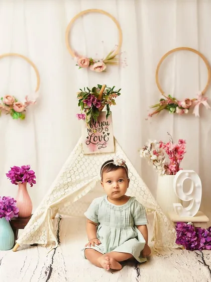 A proud sitter, posing in her beautiful floral setup. The number '9' prop subtly marks her nine-month milestone.