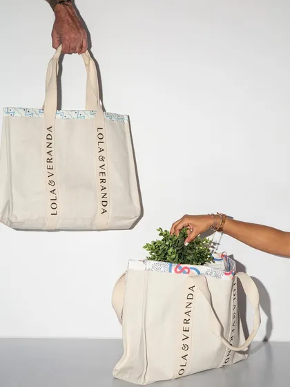 A simple yet effective shot showcasing a branded tote bag. The use of two bags and interacting hands adds a dynamic element to an otherwise minimalist composition.