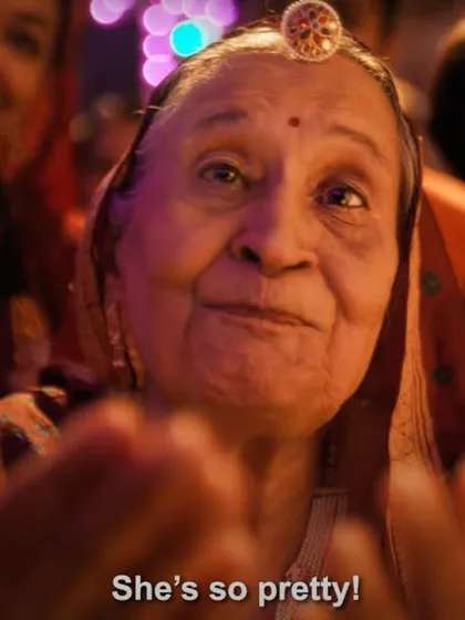 A heartwarming shot of the grandmother from the IPL ad, styled in a traditional saree and borla, looking on with love.