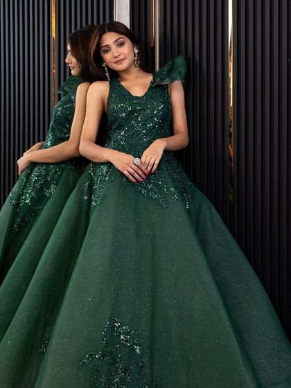 A model posing elegantly in the emerald green gown, a perfect rental for making a glamorous statement.