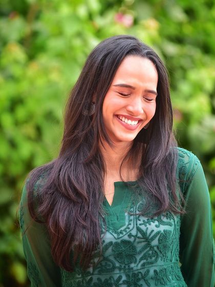 A moment of pure joy and laughter. This candid shot in a vibrant green dress against a lush background is full of life and positive energy.