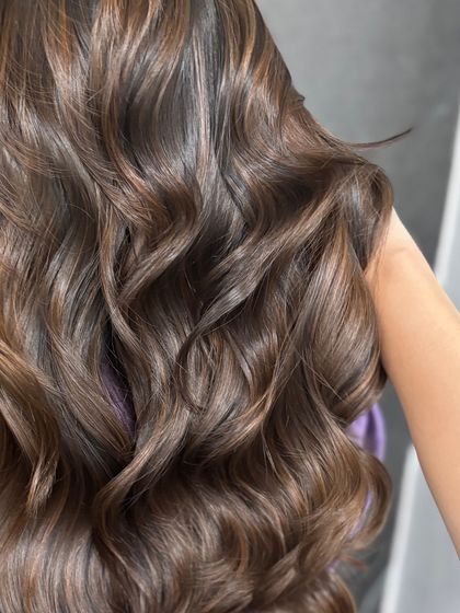 A close-up on the texture of these luxe waves, showing the health and shine of the hair after coloring and styling.