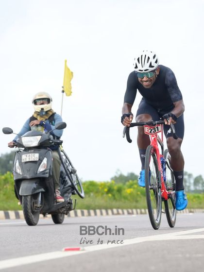 An elite rider receives a water bottle from a support moto, a crucial moment of refueling during a long race.