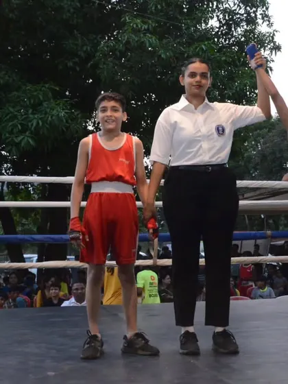 A young boxer's hand is raised in victory at the Late Abhishek Ghosalkar Memorial Tournament. We provide platforms for new talent to shine.