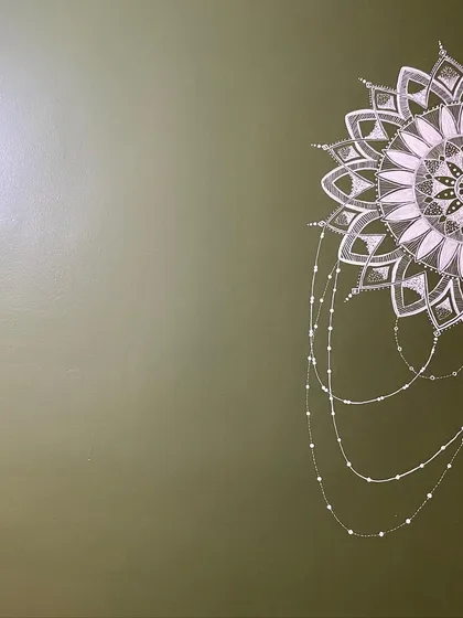 This semi-mandala was uniquely designed to wrap around a corner. The intricate white details on the olive green wall create a beautiful and continuous piece of art that flows from one space to another.