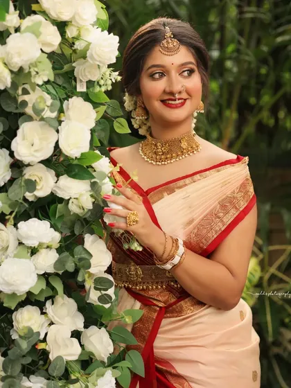 A bright and happy portrait against a wall of white flowers. The bride's joyful expression and the beautiful setting create a perfect celebratory image.