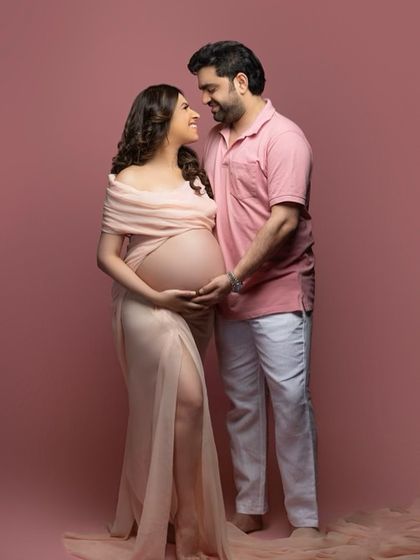 Wrapped in anticipation and surrounded by love. This sweet studio portrait against a soft pink backdrop is a beautiful way to capture the connection between a couple.