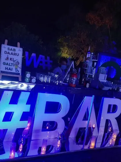I love adding a modern and fun touch to evening events. This bar setup features a large, backlit LED sign and cool blue lighting, creating a vibrant atmosphere perfect for a sangeet or cocktail night.