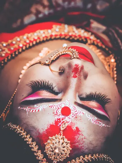 An artistic top-down shot of a Bengali bride's stunning makeup. We pay close attention to the details, capturing the artistry of the 'chandan' designs and the richness of the bridal look.