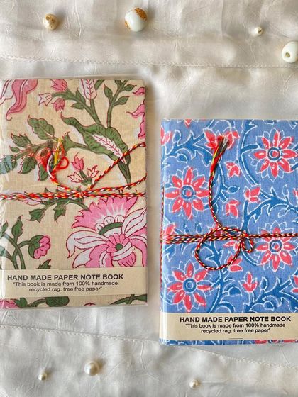 Two more of our beautiful handmade journals, one with a pink and green floral design and the other with a blue floral pattern.