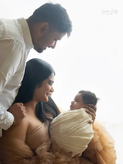 A new family of three, framed by soft window light. This classic lighting technique creates beautiful, intimate portraits.
