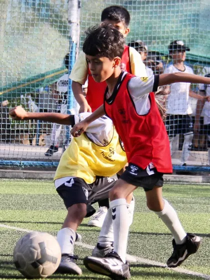 Players in red and yellow bibs compete fiercely for the ball during a small-sided game, a key part of our tactical training.