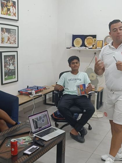 A coach leads a discussion on mental strategy, using a laptop to show match analysis. We use modern tools to give our players a competitive edge.