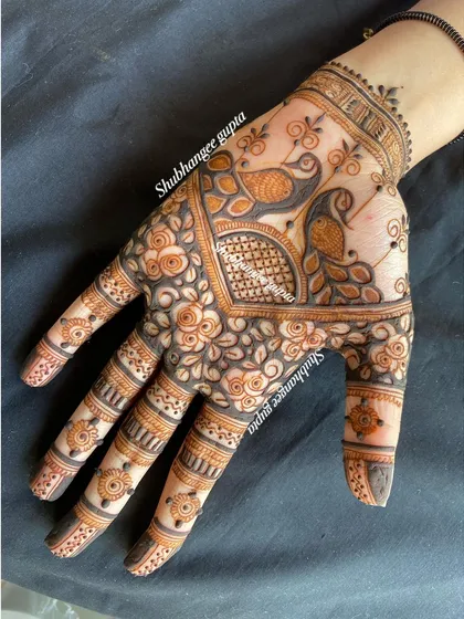 A lovely back of hand design featuring two peacocks surrounded by a frame of roses. This is a great example of combining traditional bird motifs with floral patterns.