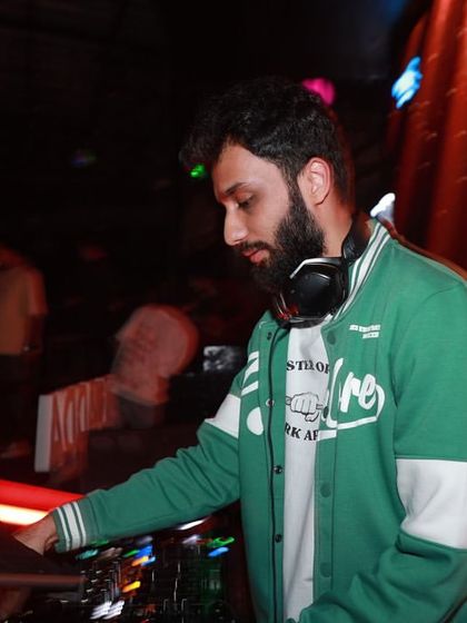 A focused shot of me working the laptop and mixer, with the club's visuals creating a dynamic background.