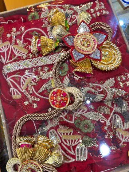 A close-up of a beautifully packed red bridal outfit. The intricate embroidery of the garment is complemented by the handcrafted embellishments I use, making the entire package a work of art.