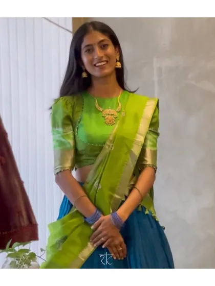 A happy client in a custom half saree, featuring a blue skirt and a vibrant parrot green blouse with puff sleeves. A classic and colorful choice for traditional events.