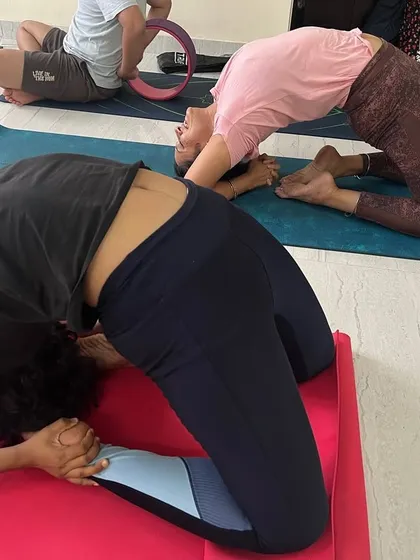 Two students practicing Kapotasana. The pose not only stretches the entire front of the body but also strengthens the back muscles and improves posture.