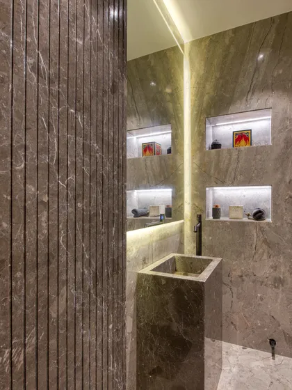 Another view of the powder room, revealing illuminated display niches reflected in the large mirror. This detail adds a layer of personalization and ambient light.