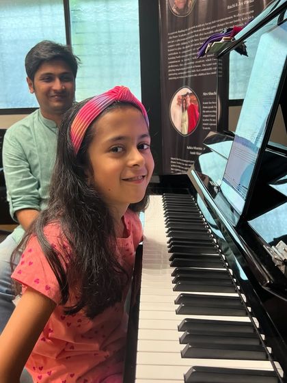 A student and teacher share a smile during a piano lesson. Our teachers build strong, supportive relationships with their students, creating a positive learning environment.
