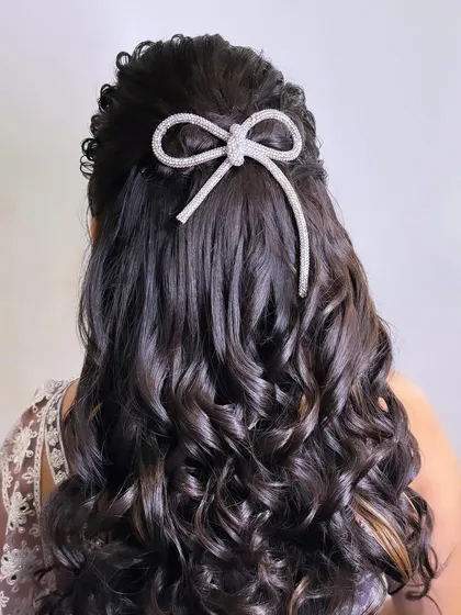 A closer look at this beautiful half-up style. The curls are perfectly defined, and the bow accessory adds a touch of modern charm.