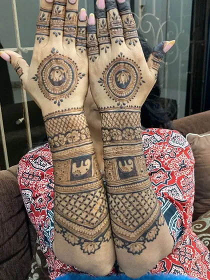 A client showing her full-arm mehandi, which features elephant mandalas on the palms and detailed check patterns on the arms.