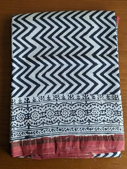 A classic black and white chevron handblock print on a silk cotton saree with a contrasting red border. This is a statement piece that is sure to turn heads.