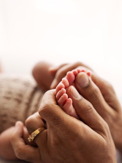 A close-up of a parent's hands cradling their newborn's feet. The detail of the tiny toes is just perfect.