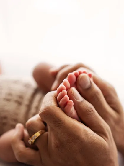 Another beautiful shot of a parent holding their baby's feet. The detail of the wedding ring adds another layer to the family story.