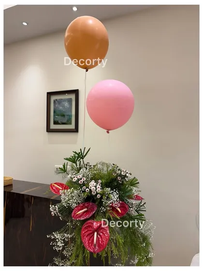 A simple yet beautiful floral arrangement with floating balloons, adding a touch of magic to a butterfly-themed party.