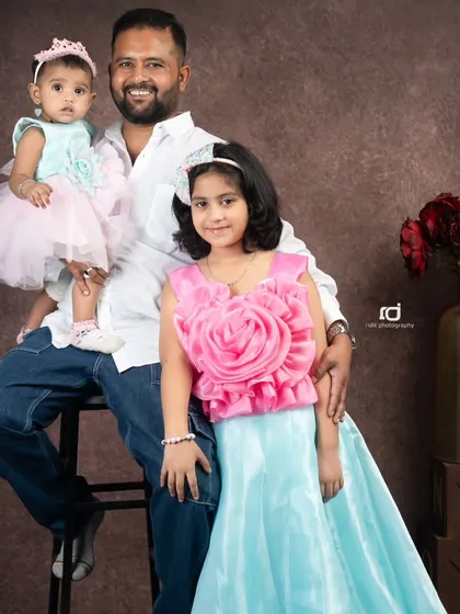 A proud father with his two lovely daughters. This portrait captures the special bond between a dad and his girls in a warm studio setting.