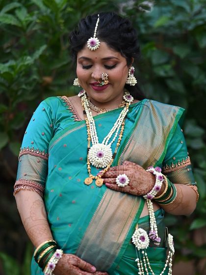 A serene portrait of the mom-to-be. The teal green saree and matching floral jewelry create a harmonious and traditional look for her baby shower.