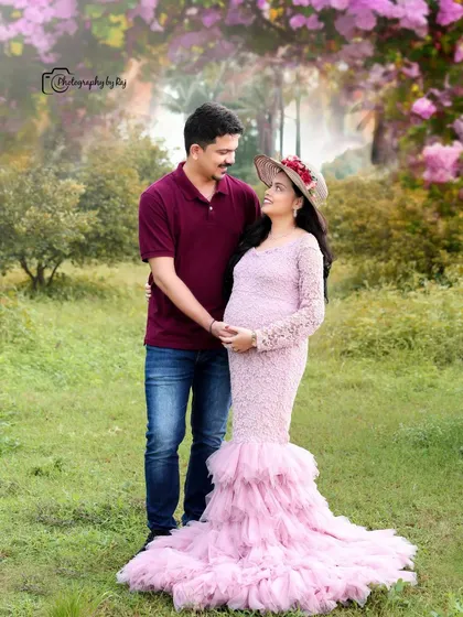 A romantic couple's portrait in a pink lace gown. The soft, dreamy edit and floral elements add to the fairytale feel of this maternity photo.