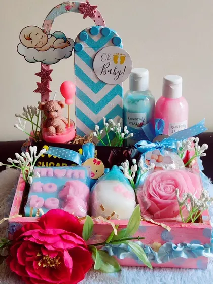 A "Mom to be" hamper with a pink and blue theme. It includes themed soaps, body wash, lotion, and other treats for the expecting mother.