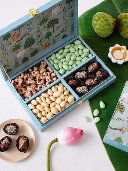 Diwali magic in every bite. This beautiful blue box is filled with four sections of our gourmet nuts and chocolate-coated dates, including Rose Cashew and Elaichi Badam.