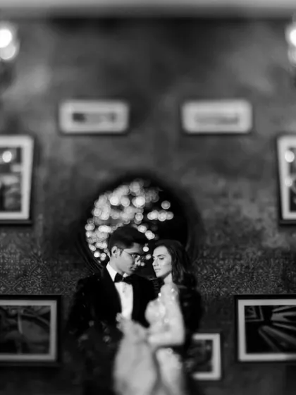 A soft-focus, dreamy monochrome portrait from a cocktail night. The bokeh lights in the background create a magical atmosphere, with the focus remaining on the couple's loving gaze.